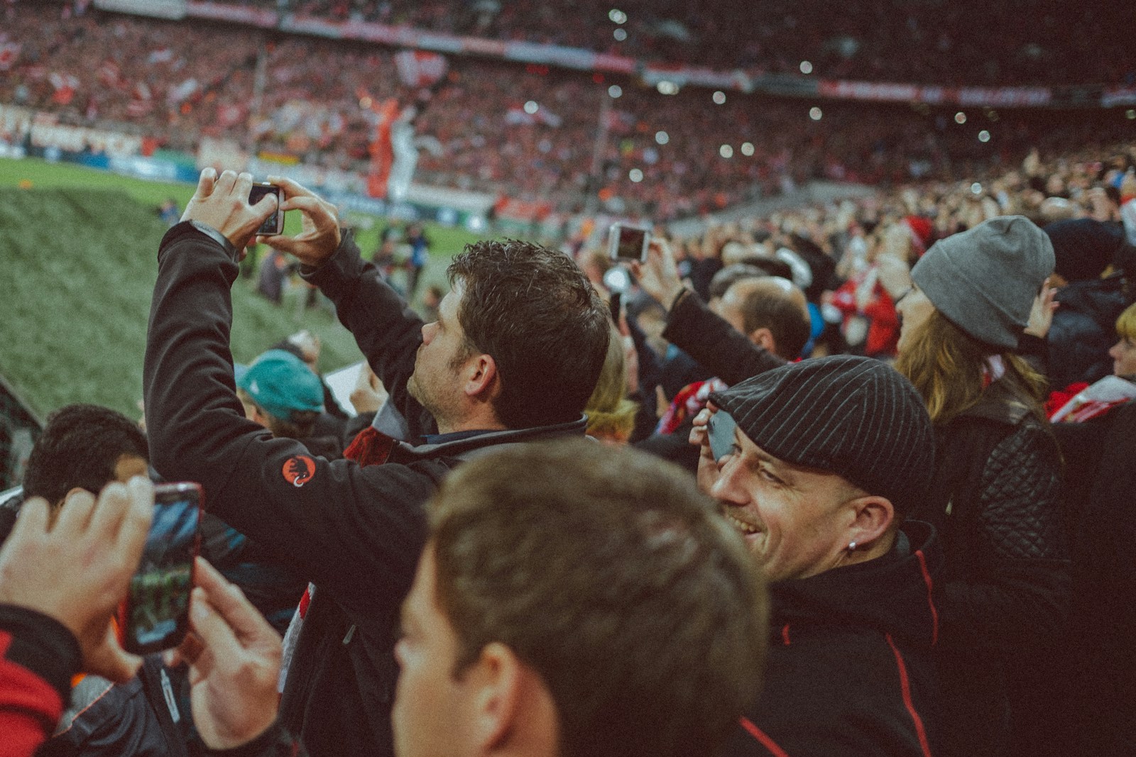 Futballszurkolók okostelefonnal rögzítenek egy stadionban zajló mérkőzést.